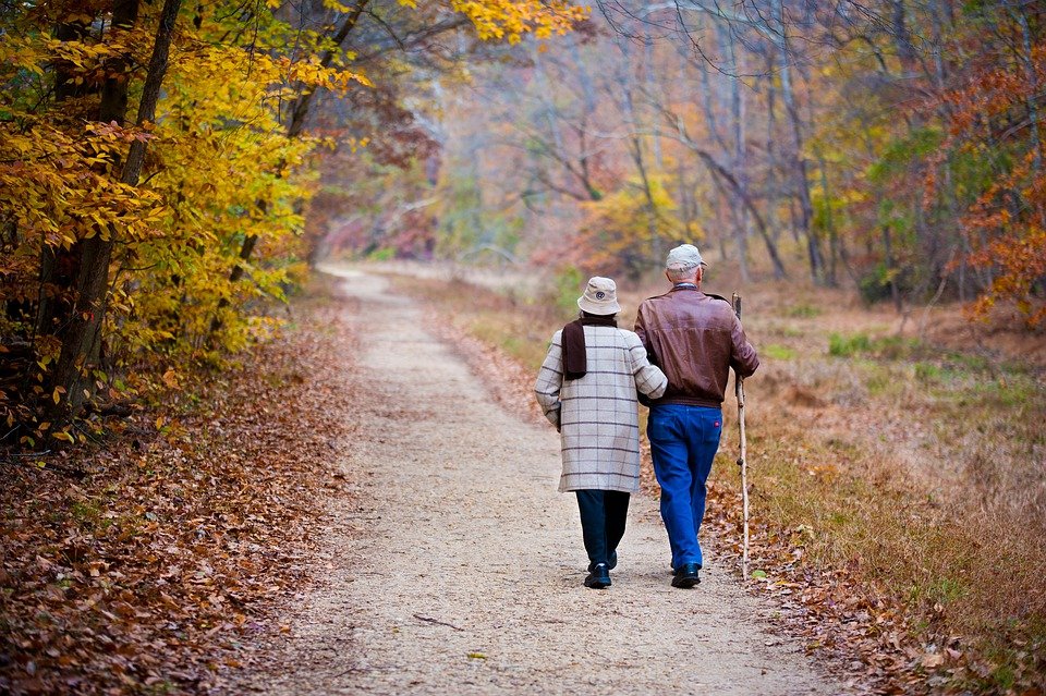 Elderly couple walking on an autumn path — pain relief and mobility therapy at Innovation Wellness